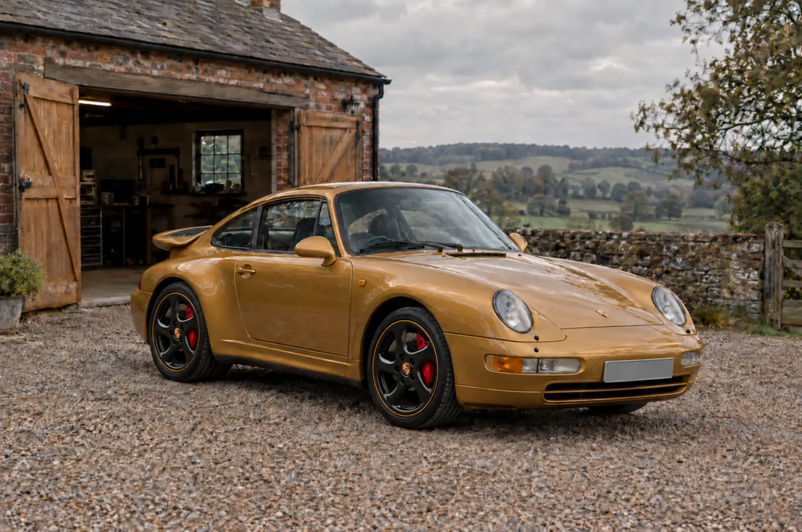 Gold Porsche 993 Turbo outside a country garage